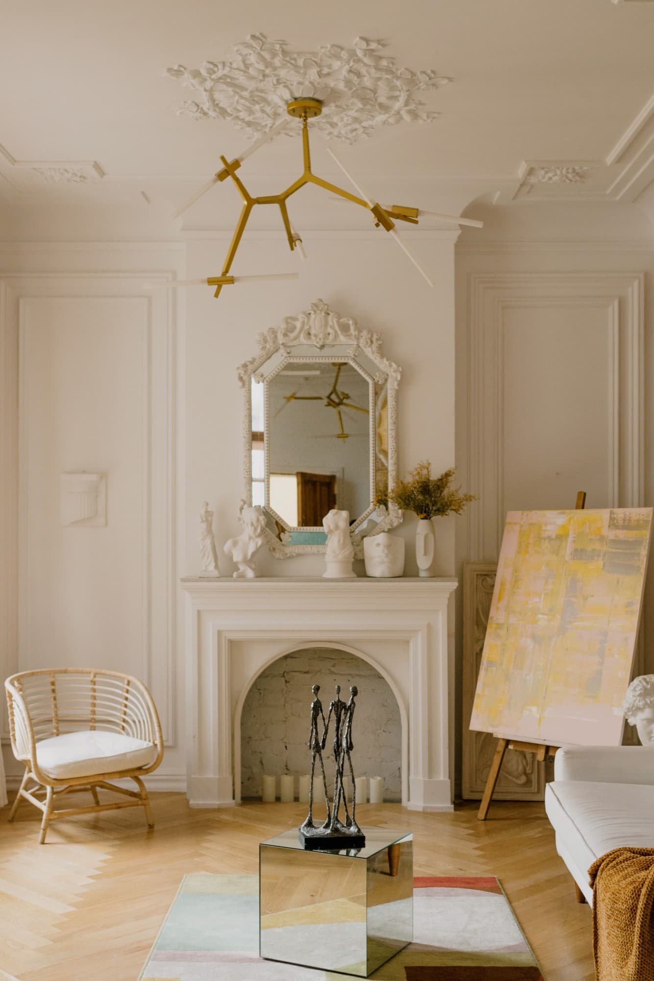 A light-filled sitting room with a sculpted fireplace and artwork